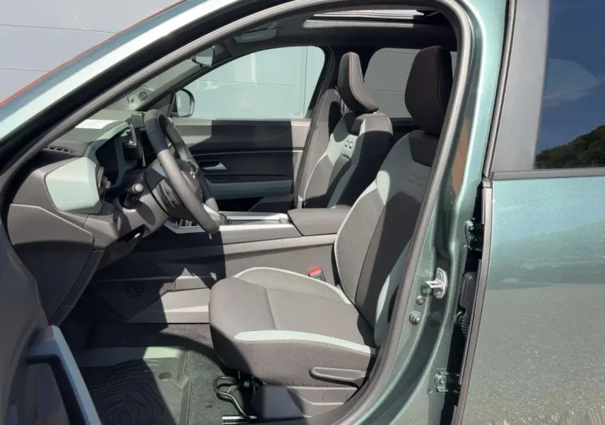 Vue intérieure côté conducteur du Dacia Bigster vert cèdre, montrant les sièges avant et le volant cuir soft feel.