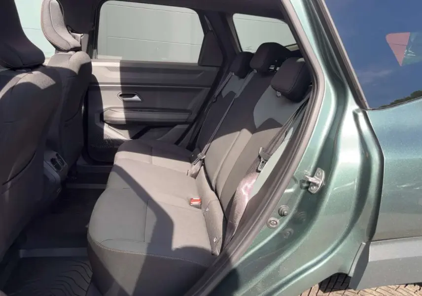 Vue latérale droite sur l'intérieur arrière du Dacia Bigster vert cèdre, montrant la banquette trois places et les finitions tissu.