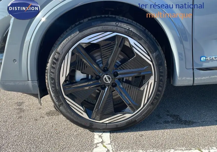 Gros plan sur l'avant droit du Nissan Qashqai gris céramique, mettant en valeur le phare LED et la jante noire à motifs blancs.