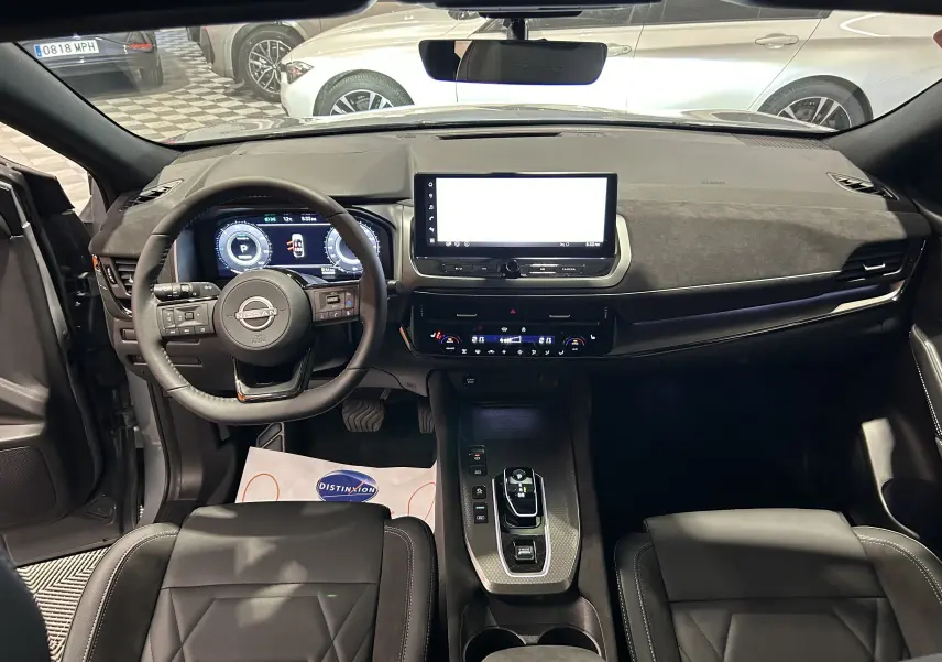 Intérieur du Nissan Qashqai 2025 vue de face, volant multifonction, écran tactile et sièges cuir noir visibles.