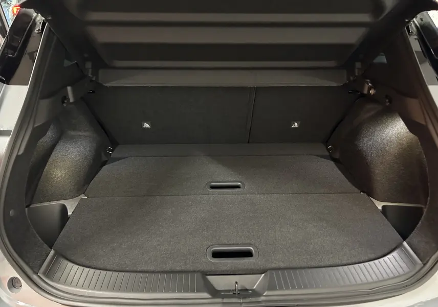 Coffre ouvert du Nissan Qashqai 2025 gris céramique, montrant un espace de chargement plat et bien fini.