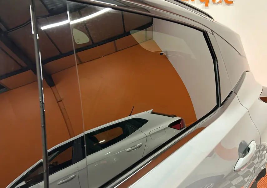 Reflet latéral droit du Nissan Qashqai gris céramique métal avec lignes de carrosserie marquées sur fond orange.