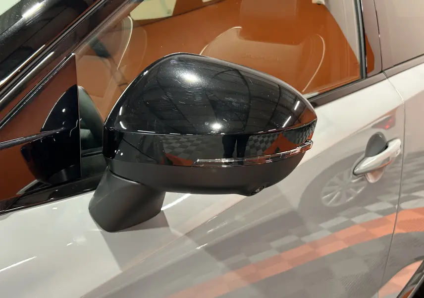 Gros plan sur le rétroviseur noir brillant côté gauche du Nissan Qashqai gris céramique avec intérieur cuir brun.