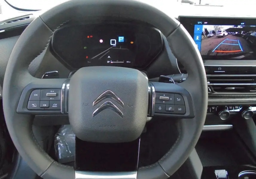 Vue intérieure centrée sur le volant noir de la Citroën C5 X 2022 avec tableau de bord digital et écran multimédia affichant la caméra de recul.