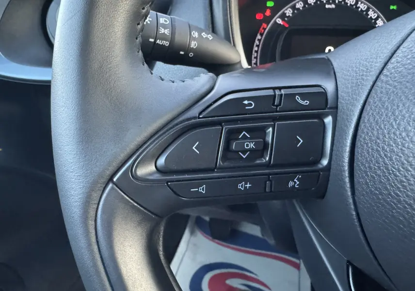 Gros plan sur les commandes au volant côté droit d'une Toyota Aygo X 2025, avec tableau de bord partiellement visible.