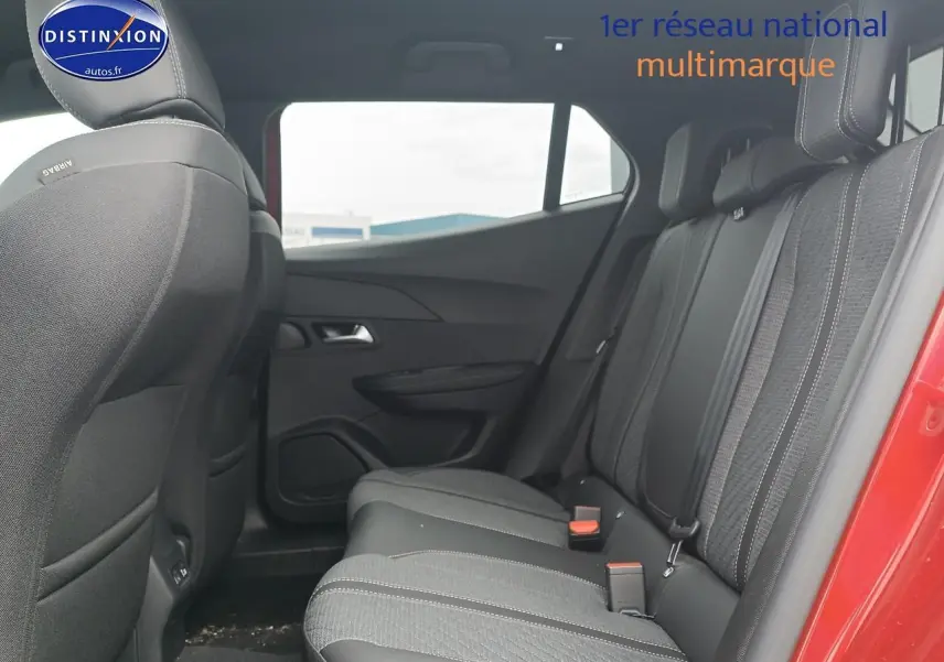 Vue latérale intérieure arrière du Peugeot 2008 rouge elixir, montrant les sièges arrière en tissu noir avec ceintures de sécurité.