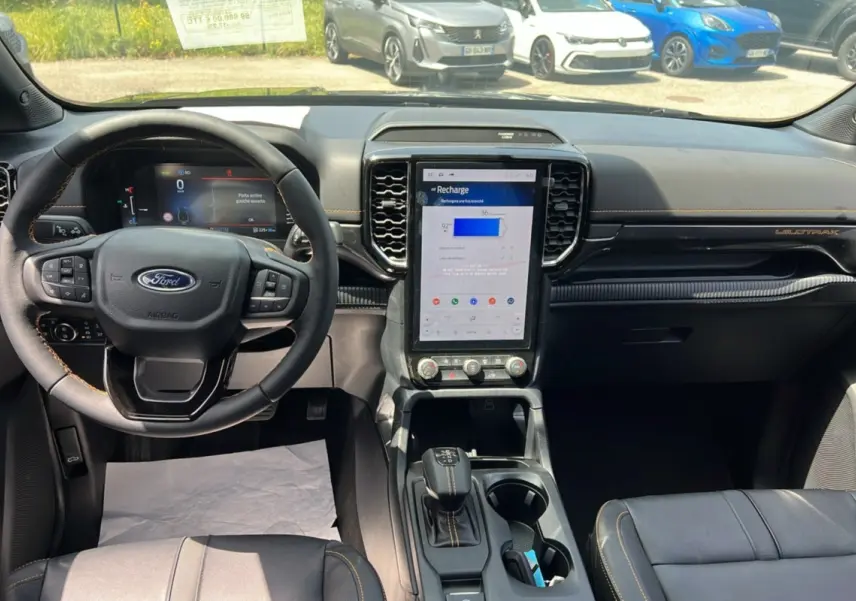 Vue intérieure du tableau de bord du Ford Ranger PHEV Wildtrak 2025 avec écran tactile vertical et volant cuir multifonctions.