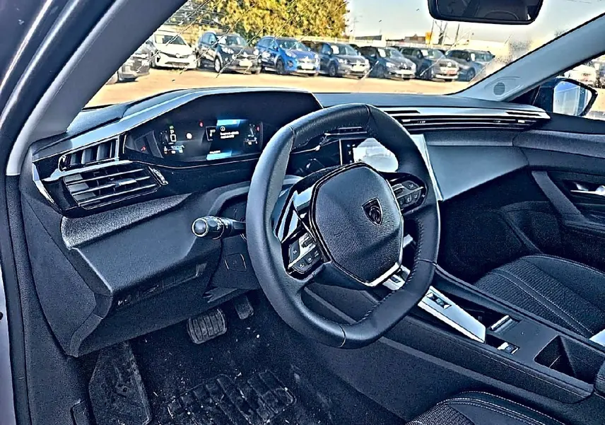 Vue intérieure côté conducteur du Peugeot 308 SW 2025, volant multifonction et tableau de bord numérique visibles.