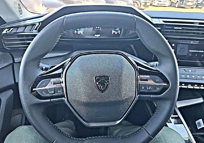 Vue rapprochée du volant multifonction noir de la Peugeot 308 SW 2025 avec tableau de bord et écran tactile visibles.