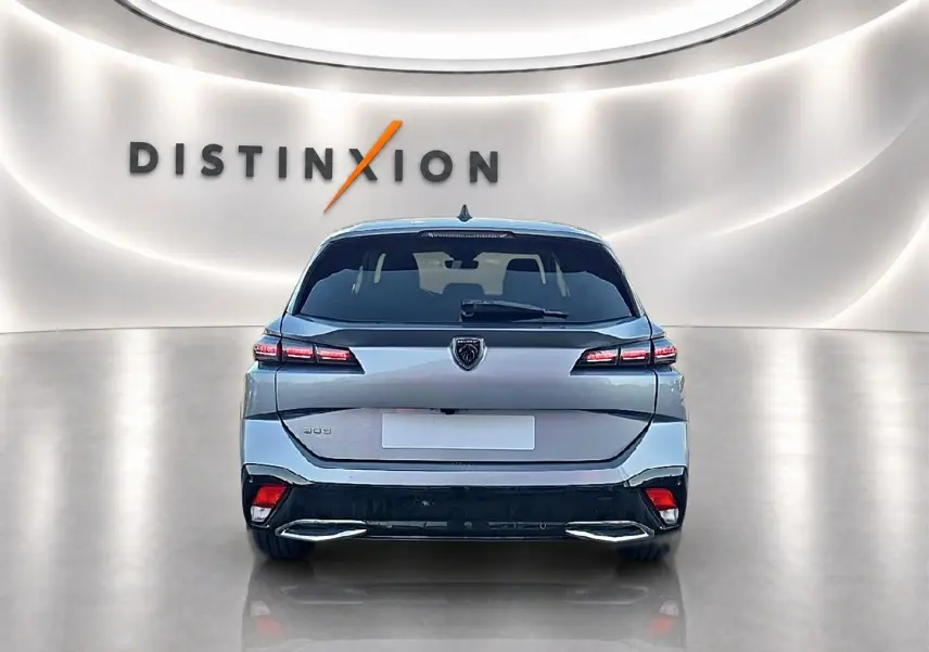 Vue arrière centrale d'une Peugeot 308 SW gris artense dans un showroom avec éclairage moderne et logo Distinxion en arrière-plan.