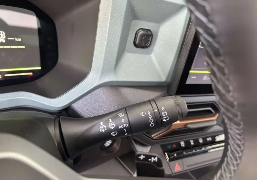 Gros plan sur la commande d’essuie-glace à gauche du volant dans l’habitacle gris du Dacia Bigster Hybrid-G 150 4x4.