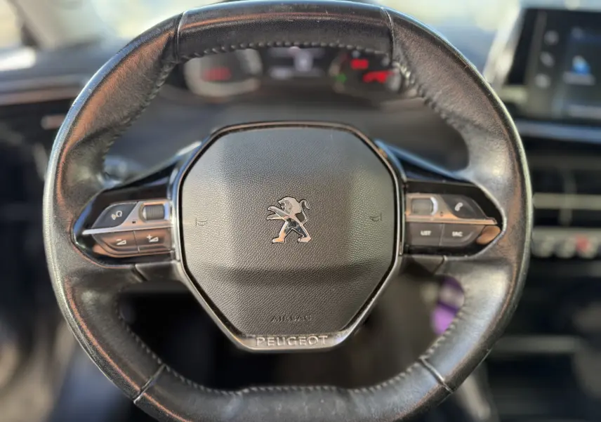 Volant en cuir noir de Peugeot 2008 1.5 HDi 100 Active 2020 avec commandes intégrées et logo lion central.