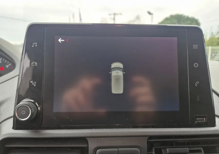 Écran tactile central affichant la vue supérieure du Peugeot Partner blanc, intérieur du tableau de bord visible.