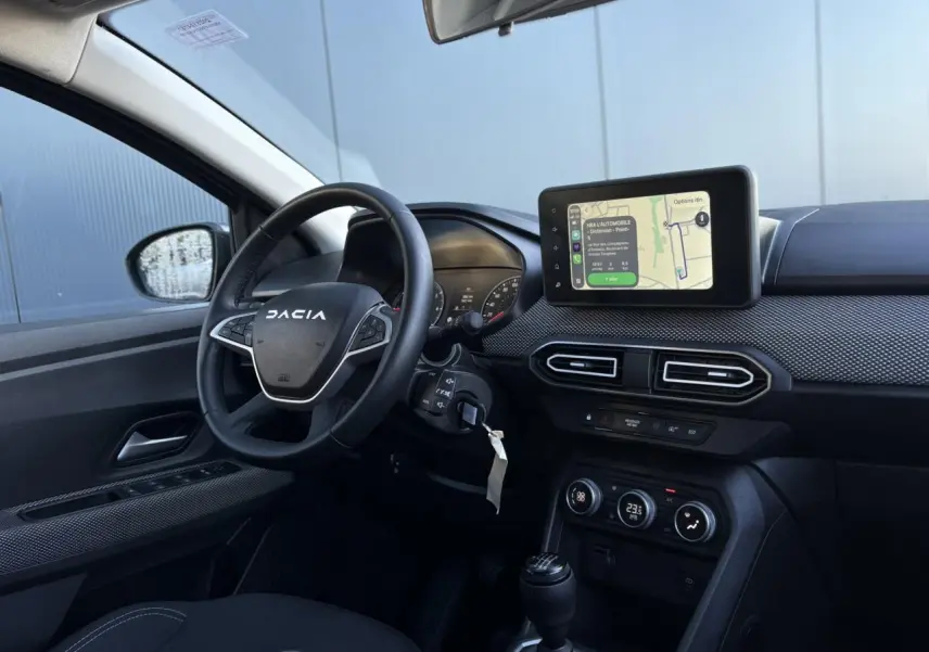 Vue intérieure côté conducteur du Dacia Jogger gris Schiste 2025, avec tableau de bord et écran tactile GPS visible.