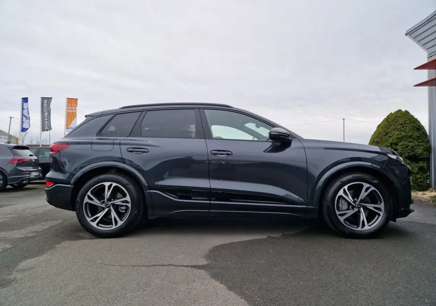 Vue de profil côté gauche d'un Audi Q6 e-tron Performance S-Line gris Manhattan avec jantes alliage distinctives.