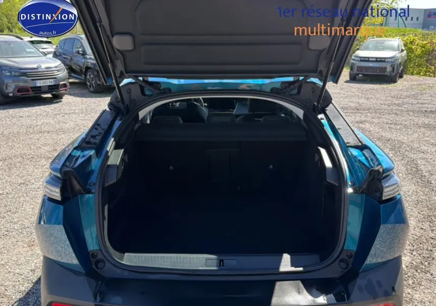 Vue arrière ouverte du coffre d'une Peugeot 408 Hybrid 145 allure bleu, montrant l'espace de chargement vide.