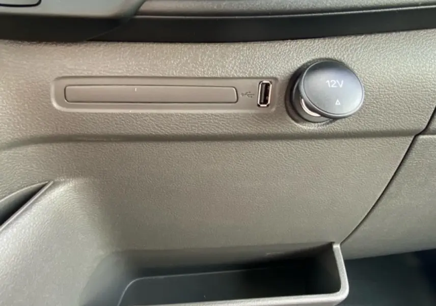 Gros plan sur la console centrale grise du Ford Transit Fourgon 2023, avec prise USB et prise 12V visibles.