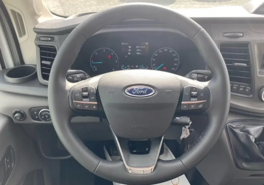 Vue intérieure centrée sur le volant multifonction du Ford Transit Fourgon 2023 avec tableau de bord numérique.