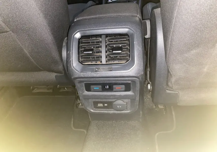 Vue rapprochée de la console arrière avec bouches d'aération et commandes de climatisation du Volkswagen Tiguan 2020 intérieur noir.