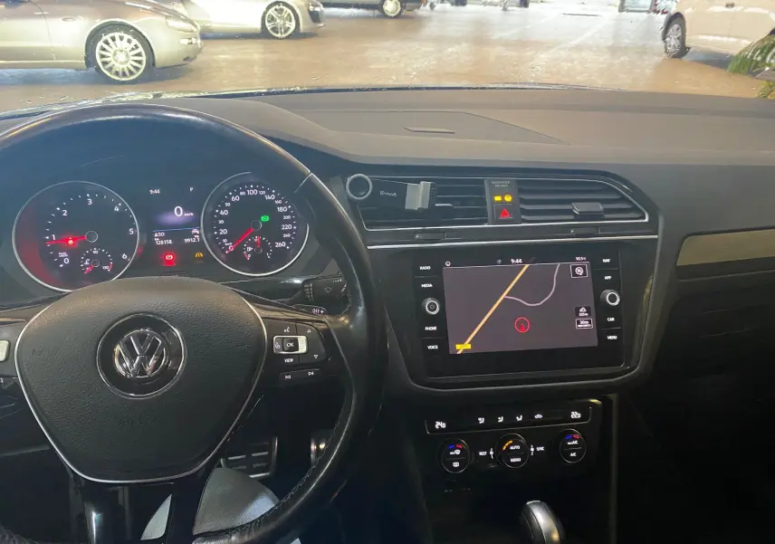Intérieur noir du Volkswagen Tiguan 2020, vue du poste de conduite avec tableau de bord et écran GPS central.