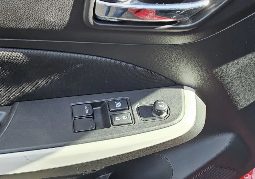 Panneau de porte côté conducteur de Suzuki Swift 2023 rouge, avec commandes des vitres et réglage des rétroviseurs.