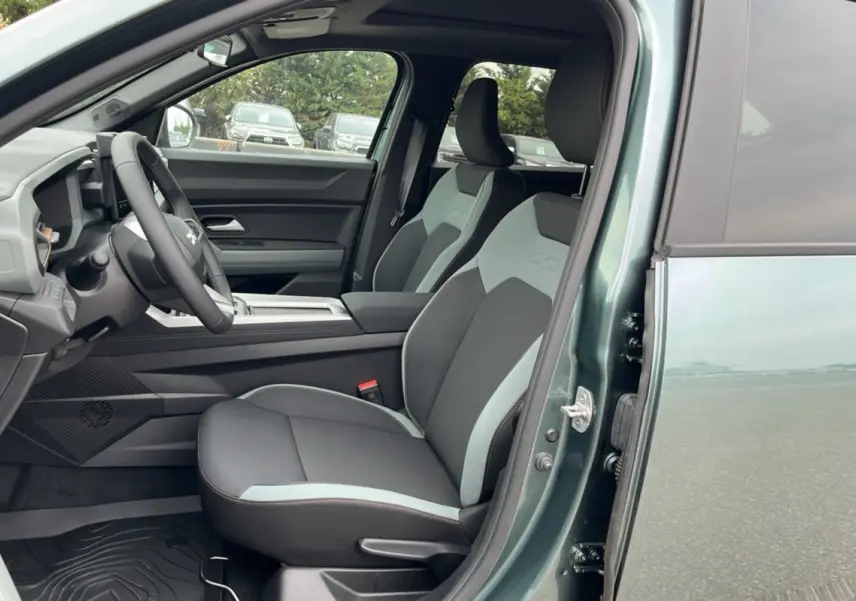 Intérieur côté conducteur du Dacia Bigster vert cèdre 2025, sièges bi-ton et tableau de bord moderne visible.