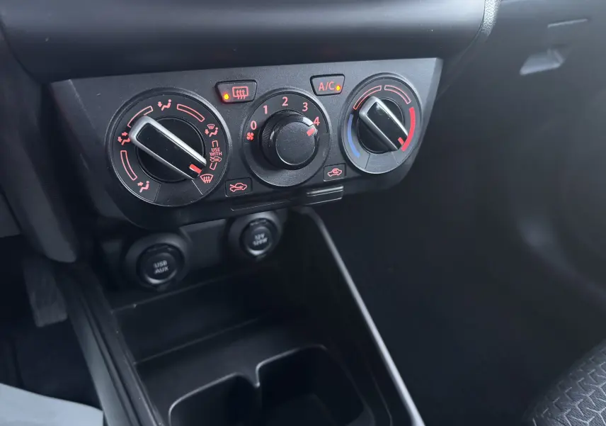 Gros plan sur les commandes de climatisation et ventilation noires du tableau de bord de la Suzuki Swift gris 2021.
