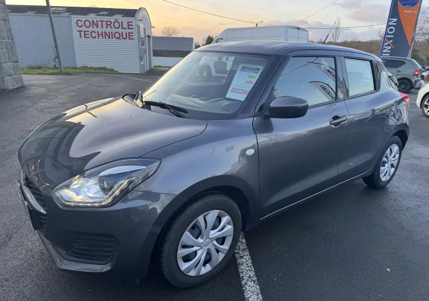 Vue 3/4 avant droite d'une Suzuki Swift 1.2 Dualjet Hybrid gris 2021, compacte avec cinq portes et jantes acier.