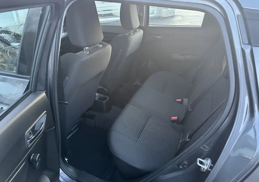 Vue intérieure côté gauche montrant la banquette arrière noire et les sièges avant d'une Suzuki Swift gris 2021.