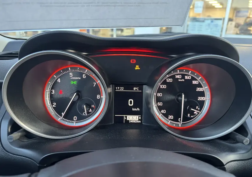 Vue rapprochée du tableau de bord de la Suzuki Swift 1.2 Dualjet Hybrid 2021 avec compte-tours et compteur de vitesse rétroéclairés en rouge.