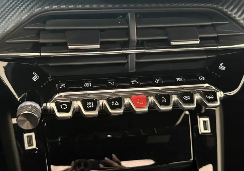 Gros plan sur la console centrale noire brillante du Peugeot 2008 GT Pack 2021 avec boutons métalliques et touches tactiles.