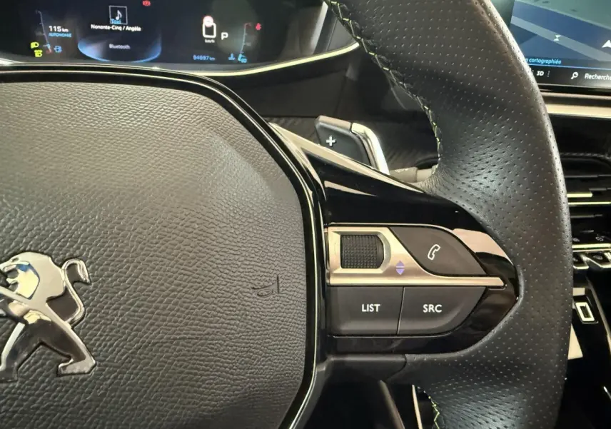 Gros plan sur le volant cuir perforé côté droit du Peugeot 2008 GT Pack 2021 avec commandes audio et écran numérique en arrière-plan.
