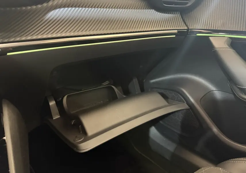Gros plan sur la boîte à gants ouverte et le tableau de bord noir avec insert décoratif effet carbone du Peugeot 2008 GT Pack.