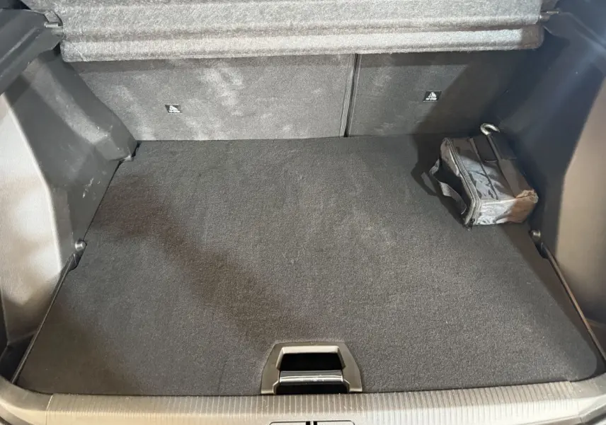 Coffre ouvert du Peugeot 2008 bleu, vue de dessus montrant un espace de rangement propre avec sac noir à droite.