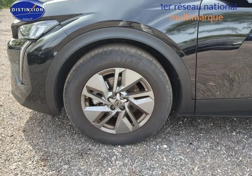 Gros plan sur la roue avant gauche d’une Peugeot 408 bleu foncé avec jante alu au design moderne.