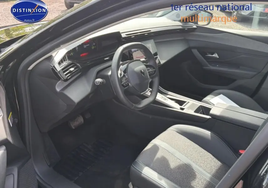 Vue intérieure côté conducteur de la Peugeot 408 Hybrid 136 allure 2024 avec volant cuir et console centrale moderne.