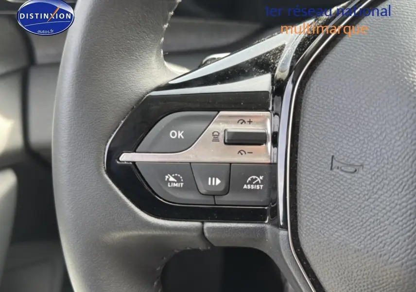 Gros plan sur les commandes du volant cuir noir de la Peugeot 408 Hybrid 136 allure e-dcs6, boutons multifonctions visibles.