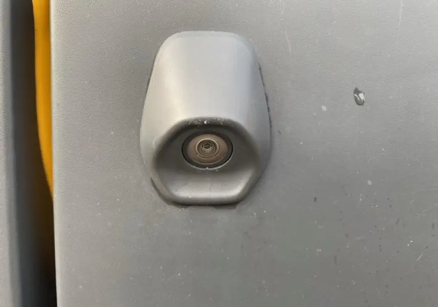 Gros plan sur la caméra de recul intégrée à la porte arrière grise du Ford Transit Fourgon orange.