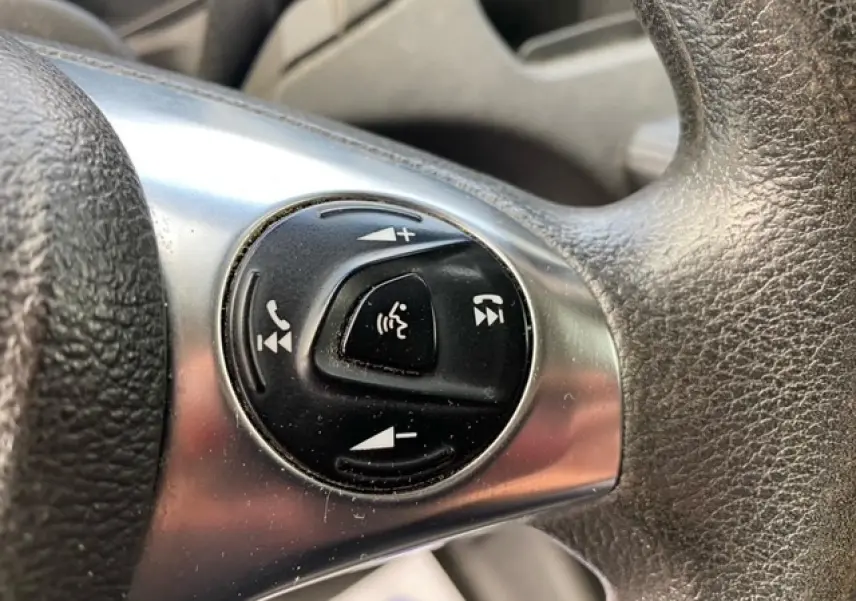 Gros plan sur les commandes audio et téléphone intégrées au volant noir du Ford Transit Fourgon orange de 2015.