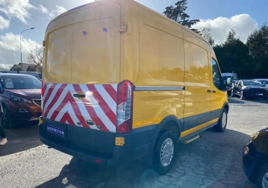 Vue 3/4 arrière droite d’un Ford Transit fourgon orange avec bandes réfléchissantes rouges et blanches sur les portes arrière.