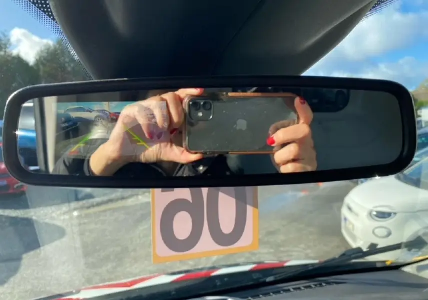 Vue intérieure du rétroviseur central du Ford Transit Fourgon orange, avec reflet du conducteur et caméra de recul visible.