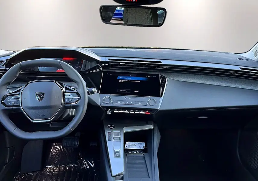 Vue intérieure avant du tableau de bord et volant noir de la Peugeot 308 SW 2025 avec écran tactile central et commandes au volant.
