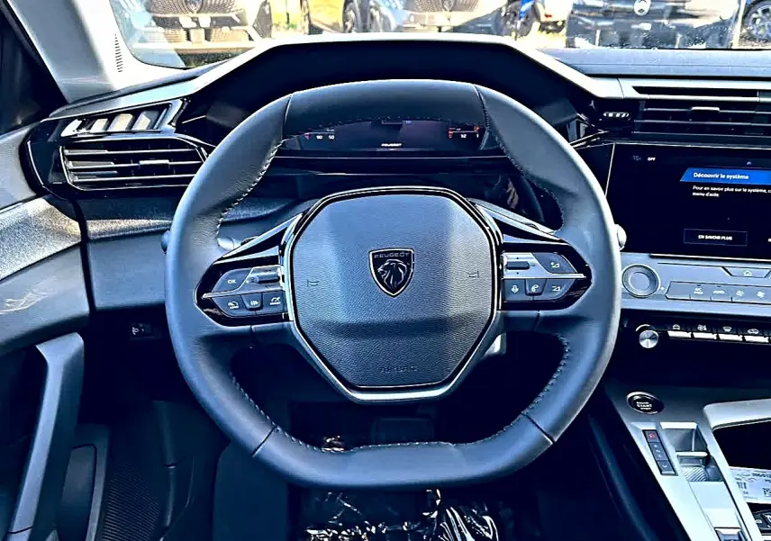 Vue intérieure centrée sur le volant multifonction noir de la Peugeot 308 SW 2025 avec tableau de bord digital et écran tactile.