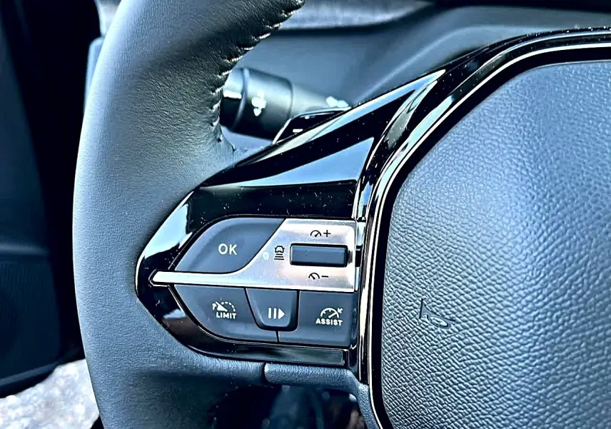 Gros plan sur le volant noir multifonction de la Peugeot 308 SW 2025 avec commandes de régulateur de vitesse.