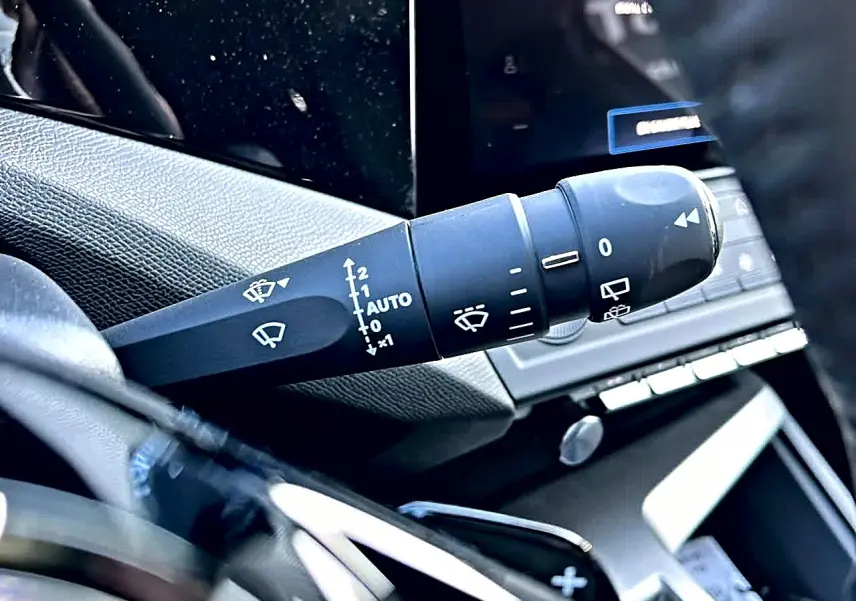 Gros plan sur la commande de l’essuie-glace côté gauche du tableau de bord d’une Peugeot 308 SW noire.