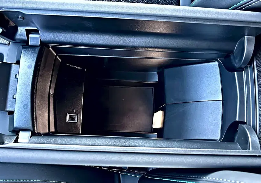 Vue plongeante sur l'accoudoir central avant noir ouvert du Peugeot 308 SW 2025 avec prise USB intégrée.