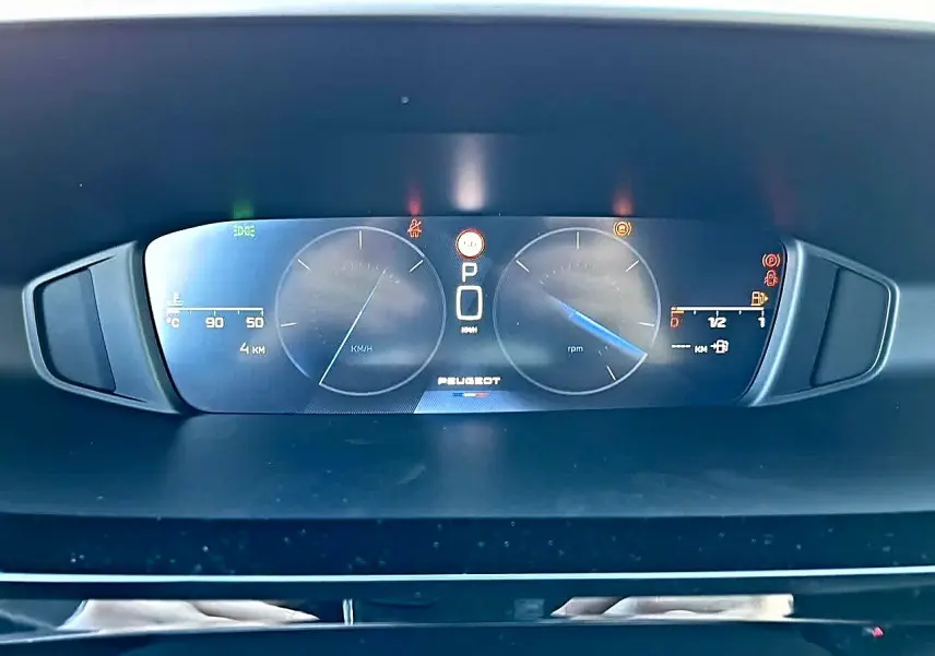 Vue rapprochée du tableau de bord numérique de la Peugeot 308 SW 2025, affichage clair avec logo central et compteurs digitaux.