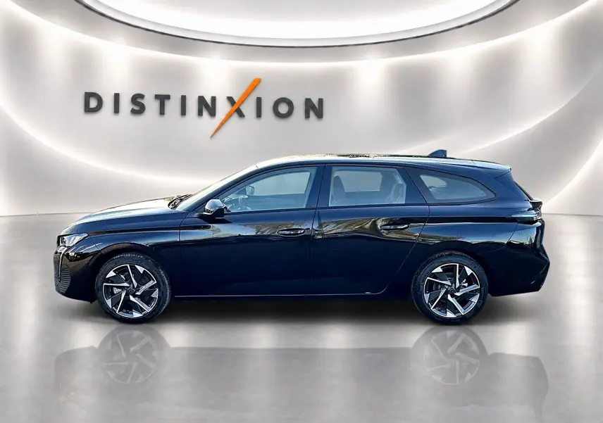Profil côté gauche d'une Peugeot 308 SW noire 2025 avec jantes alliage et vitres teintées, sur fond lumineux intérieur.