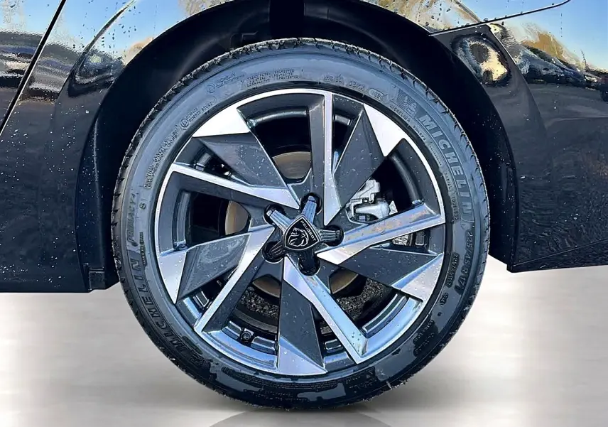 Gros plan sur la jante alu bicolore du côté arrière droit d’une Peugeot 308 SW noire avec pneu Michelin.