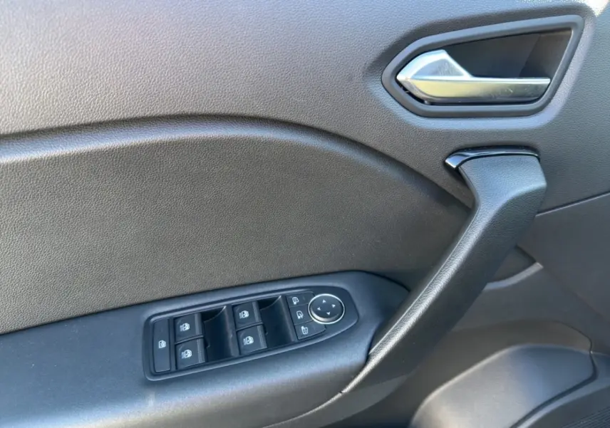 Détail de la porte côté conducteur du Renault Captur gris foncé, avec commandes électriques des vitres et poignée intégrée.